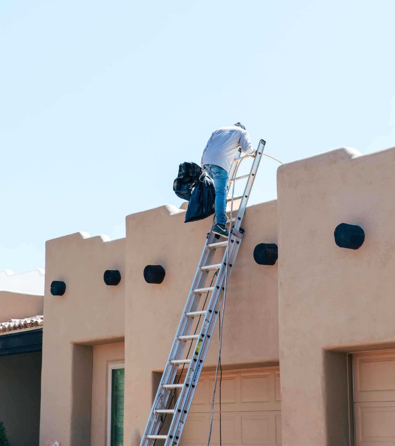 Man Climbing Ladder Onto Roof