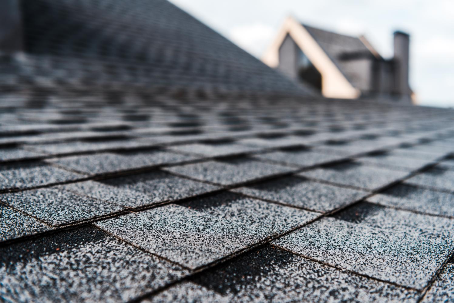 RENCO Roofing selective focus of grey shingles on rooftop building