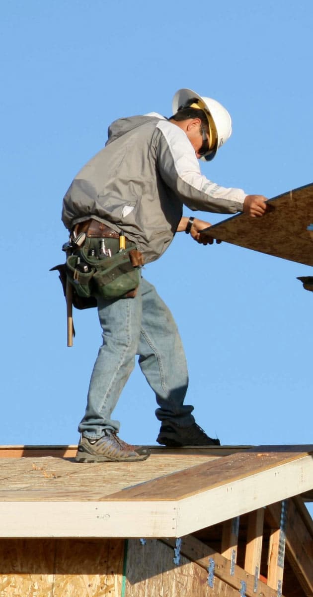 Roofer removing sheets of plywood for roof installation