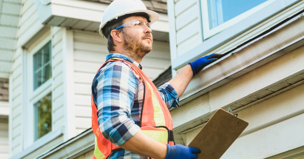 Man looking at gutters and roof for damage