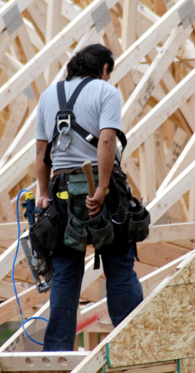 Worker grabbing framing hammer for roof installation