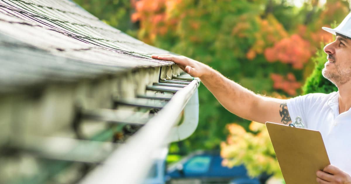 Man inspecting roof and gutters for damage