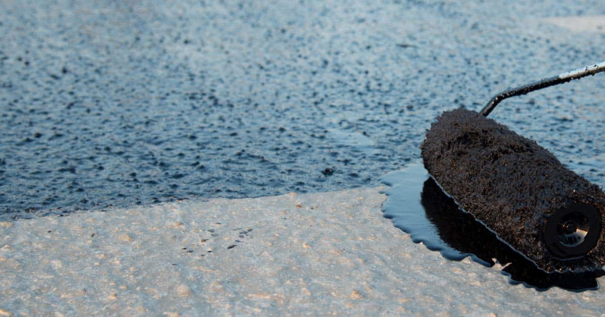 Close up image of tar-like roof coating be applied