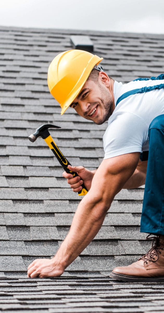 Man working on roof holding hammer in his hand