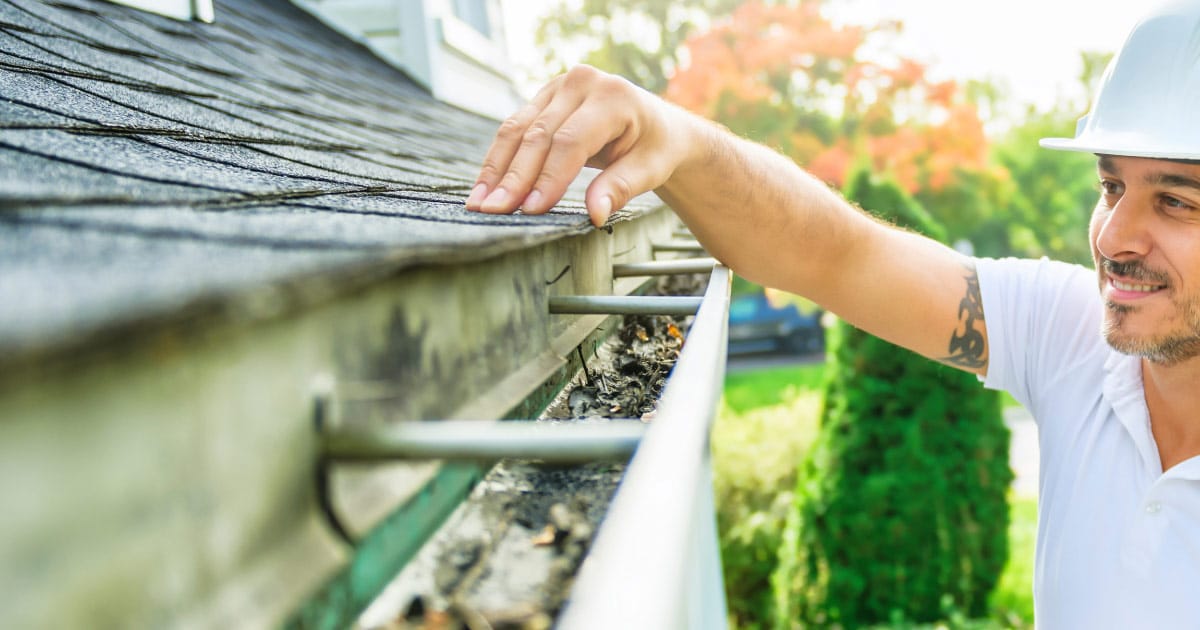 Roofing professional inspecting roof and gutter system